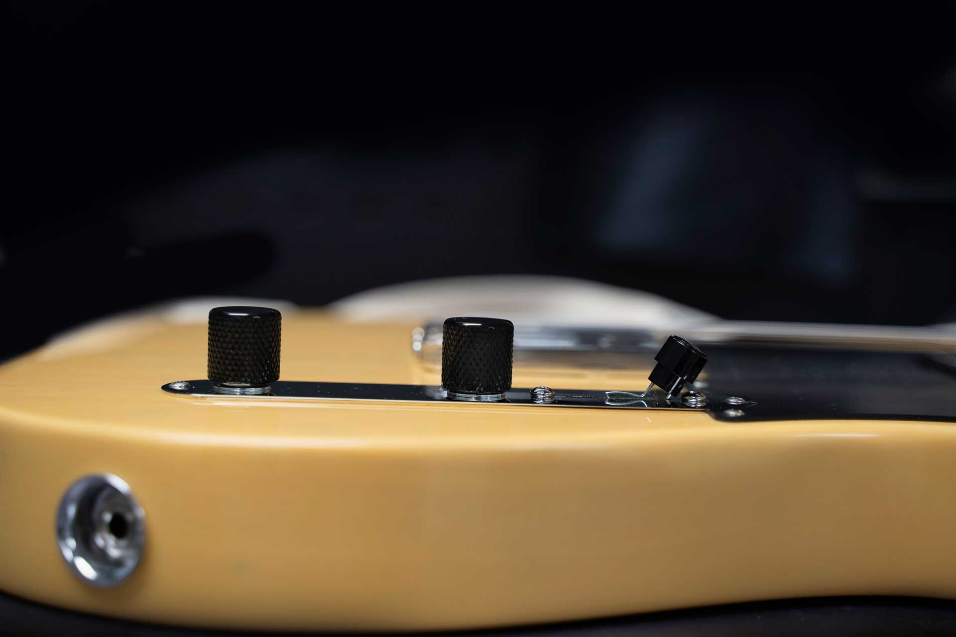 Close-up of a guitar's control knobs with a blurred background